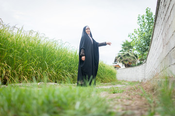 Beautiful happy Muslim woman in green field