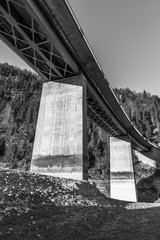 Brücke mit Betonpfeiler über einen Untergrund aus Geröll und Stein