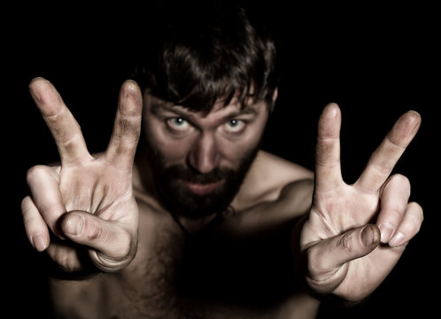 Dark portrait of scary evil sinister bearded man with smirk, shows sign of Victory. strange Russian man with a naked torso