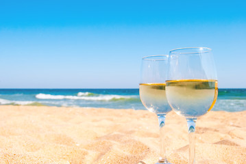 Two glasses of white wine on tropical beach. Romantic idea for couple.
