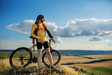 Fototapeta na wymiar Cyclist riding a bike on off road to the sunset