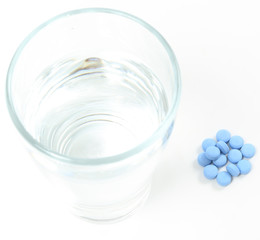 Blue piils and a water glass