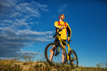 Fototapeta na wymiar Cyclist man standing on top of a mountain with bicycle