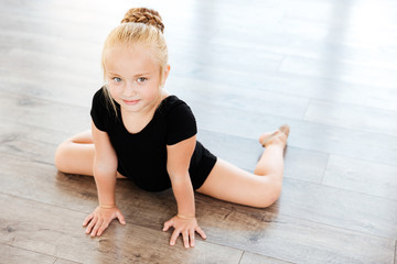 Little girl ballerina stretching in dance studio