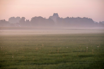 Fototapeta premium Dutch old churchtower in mist. Small rural village. Geesteren.