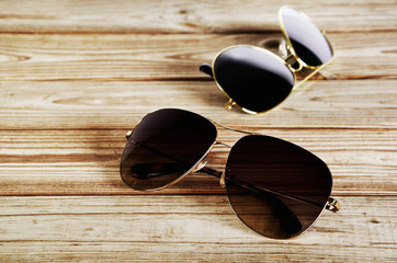 two unisex sunglasses close-up on a wooden background top view