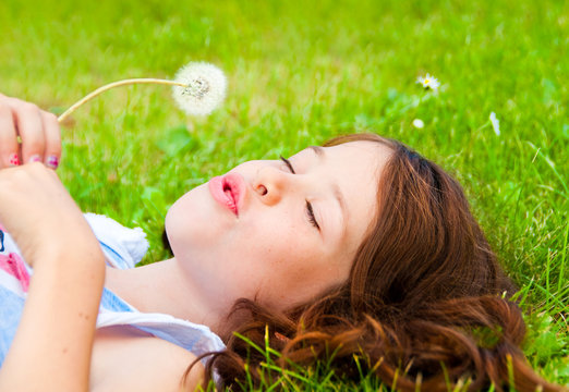Child lying on grass with a dandalion