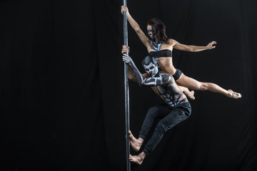 Posing of pole dance couple in dark studio