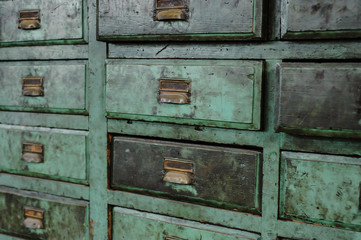 Row of green drawers with old bronze handles