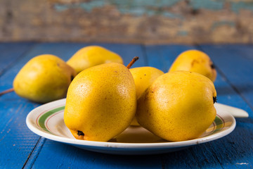 Fresh ripe organic yello pears on blue rustic wooden table, natural background, diet food.