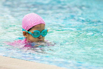 Little girl learning to swim in a swimming pool