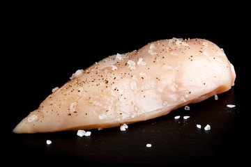 Whole skinned deboned raw chicken breast  with rock salt and black pepper.