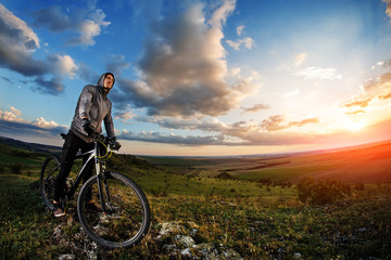 Fototapeta na wymiar Young man cycling in a summer meadow at sunset