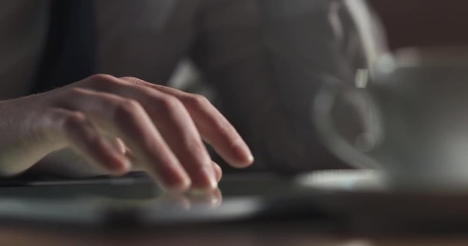 young girl using tablet pc on a table in cafe and drinking coffee