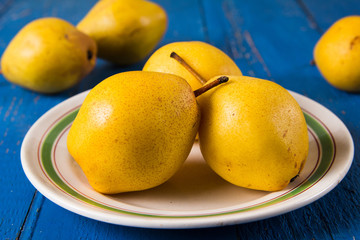 Fresh ripe organic yello pears on blue rustic wooden table, natural background, diet food.