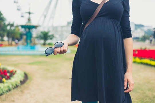 Pregnant woman in park with sunglasses