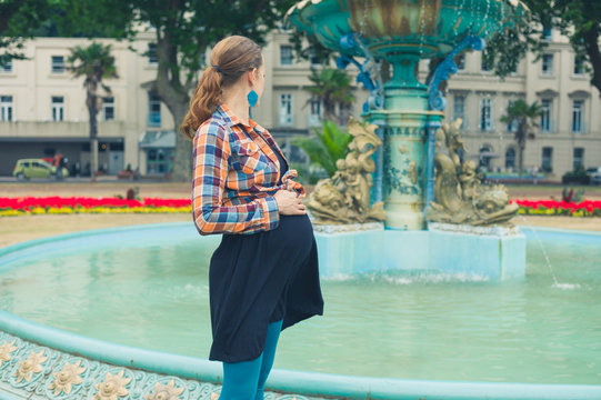 Pregnant woman by fountain in park