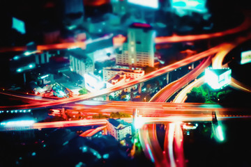 Obraz premium Blurred abstract futuristic night cityscape aerial view panorama with illuminated skyscrapers and city traffic across streets. Bangkok, Thailand