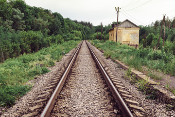 Fototapeta na wymiar railway tracks in the woods and a house with an edge