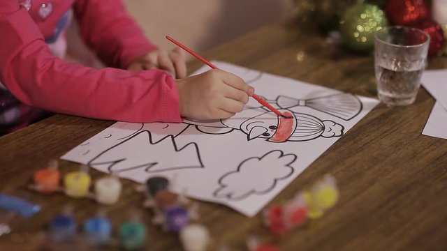 beautiful girl draws a picture of a Christmas tree and a snowman.