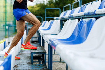 Athletic male with muscular legs up stairs of stadium outdoors