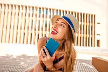 Portrait of a young smiling woman with phone outdoors on the modern wall background