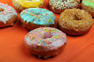 Fresh tasty donuts in soft colorful glaze on a orange wooden background