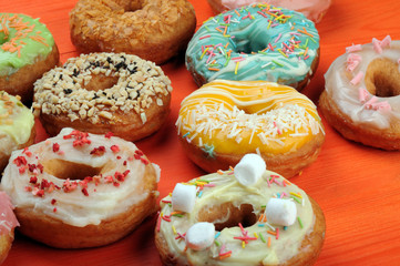 Fresh tasty donuts in soft colorful glaze on a orange wooden background
