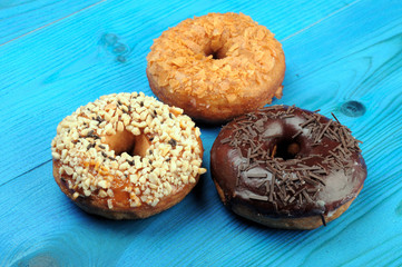 Fresh tasty donuts in soft colorful glaze on a blue wooden background