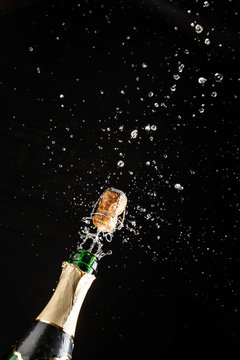 Closeup of champagne explosion. Vertical image on black background