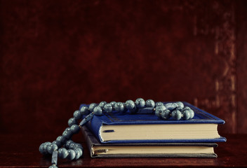 Rosary beads and prayer books on table