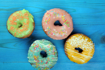 Fresh tasty donuts in soft colorful glaze on a blue wooden background