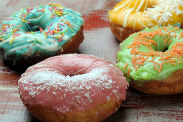 Fresh tasty donuts in soft colorful glaze on a grunge red white golden wooden background