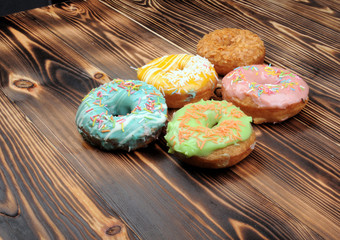 Fresh tasty donuts in soft colorful glaze on a grunge dark aged wooden background