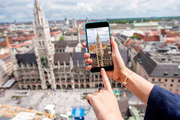 Photographing with smart phone the clock tower of the town hall in Munich city, Germany