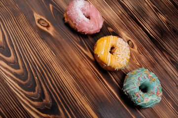 Fresh tasty donuts in soft colorful glaze on a grunge dark aged wooden background