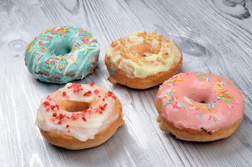 Fresh tasty donuts in soft colorful glaze on a silver wooden background
