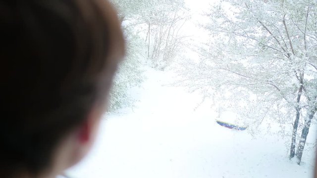 a guy looks out the window at the snowfall