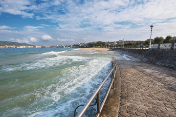 Tourist walking in the promenade of La Concha beach in San Sebastian bay, Basque Country, Spain.