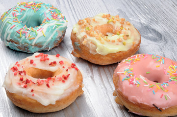 Fresh tasty donuts in soft colorful glaze on a silver wooden background