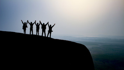 silhouette group of young people on top of the mountain