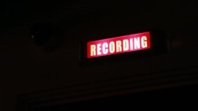 Rack focus of an active 'recording' sign in a music studio.