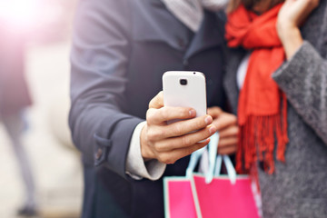 Midsection of couple shopping in the city with smartphone