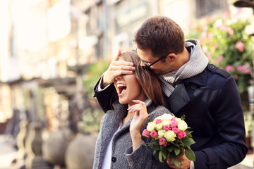 Young man surprising woman with flowers