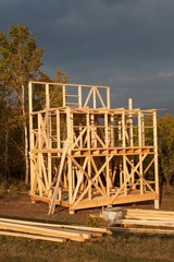 Obraz premium Sunny evening at the construction site of a wooden house. Unfinished house. 
