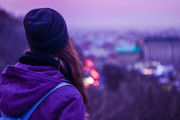 Girl looking at winter evening cityscape, purple violet sky and