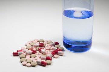 Group of tablet, antibiotic capsule and glass of water  on white