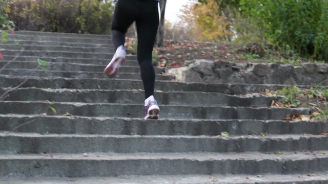 Young woman running up the stairs and going on the scamper in the autumn park