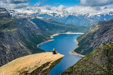 Amazing view with Trolltunga and a girl sitting on it. Norway - obrazy, fototapety, plakaty