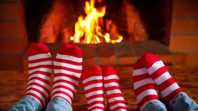 Family in Christmas socks near fireplace. Mother; father and baby having fun together. People relaxing at home. Winter holiday Xmas and New Year concept